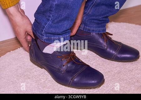 Im Schlafzimmer zieht ein Mann Schuhe an und wo man arbeiten kann Stockfoto