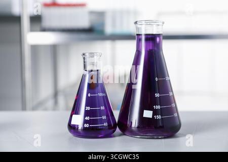 Kolben mit violetter Flüssigkeit auf dem Leuchttisch im Innenbereich Stockfoto