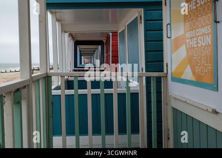 Farbenfrohe Strandhütten in Southwold, Suffolk, mit sich wiederholender perspektivischer Aussicht entlang der Balkone mit Blick auf die Sandküste. Stockfoto