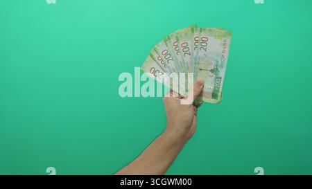 Männliche Hand, die russische Rubelscheine isoliert vor einem leuchtenden grünen Hintergrund hält, zeigt das Finanzkonzept in einem einfachen, aber auffälligen mann Stockfoto