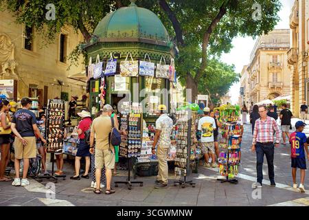 Valletta, Malta - 26. August 2025: Touristen kaufen an einem geschäftigen Straßenmarkt an einem sonnigen Sommertag bunte Souvenirs. Stockfoto