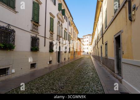Ruhige Kopfsteinpflasterstraße in Udine mit farbenfrohen historischen Gebäuden und verschlossenen Fenstern Stockfoto