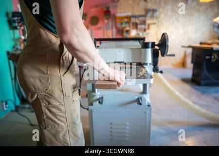Erfahrener Handwerker, der mit Holz an Hobeldickengelenken arbeitet, Möbelmaterialien vorbereitet Stockfoto