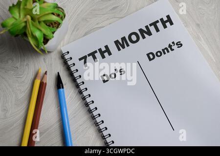 Das Konzept des 7. Monats schreibt auf einem Buch, das auf einem Holztisch isoliert ist. Stockfoto