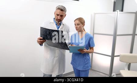 Ärzte untersuchen zerebrovaskuläres MRT-Bild des Gehirns während einer ärztlichen Sprechstunde für Patienten mit Kopfschmerzen und Schwindel. Magnetresonanzangiog Stockfoto
