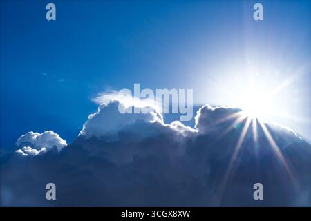 Helle Sonnenstrahlen brechen hinter großen Kumuluswolken in einem tiefblauen Himmel auf. Atmosphärischer Natur Hintergrund symbolisiert Hoffnung, Spiritualität, Wetter, insp Stockfoto