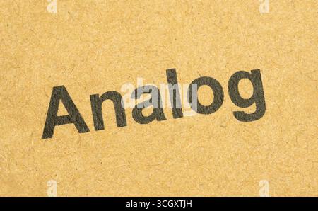 Word Analog in Schwarz auf brauner Kartonverpackung gedruckt, Makronaht mit Papierstruktur und Typografie-Schriftzug. Analoge Medien Abstract c Stockfoto
