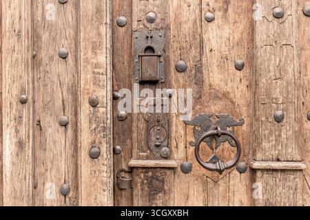 Nahaufnahme einer alten antiken Holztür mit kunstvollem Metallgriff und verwitterter Oberfläche mittelalterlicher Gebäudeeingangstor, historisches Kirchenschloss Stockfoto