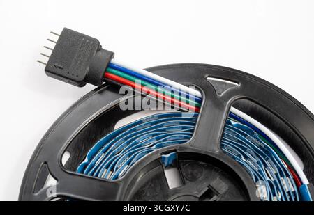 Nahaufnahme einer RGB RGBWW LED-Lichtleiste mit 5-poligem Steckverbinder und farbcodierten Drähten auf der Rolle, detaillierte Ansicht der Komponente der intelligenten Beleuchtungstechnologie fo Stockfoto