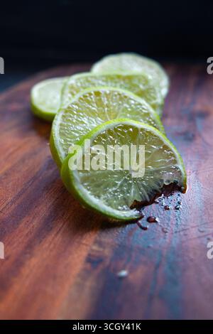 Zitronen auf einem Holzteller geschnitten. Hintergrundtapete für Speisen und Obst. Buntes Foto von frischen Zitronen. Limette und Zitrusfrüchte. Stockfoto