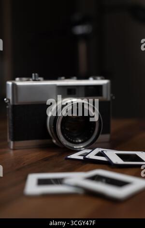 Vintage-Filmkamera und Fotodias auf einem Holztisch, die das Wesen der klassischen Fotografie und traditionellen Dunkelkammertechniken festhalten Stockfoto