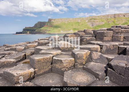 Sechseckige Basaltsäulen am Giants Causeway in Nordirland mit Sonnenschein, die an die Legende eines Riesen-Damms zwischen Irland und Schottland erinnern Stockfoto