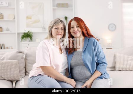 Schwangere Frau und ihre Mutter auf dem Sofa zu Hause Stockfoto