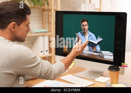 E-Learning-Konzept. Schüler, der Online-Videochat mit dem Lehrer über einen Computer am Schreibtisch führt Stockfoto