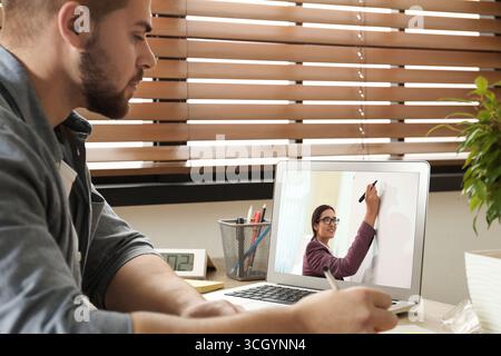 E-Learning-Konzept. Schüler, der Online-Videochat mit dem Lehrer über Laptop am Schreibtisch führt Stockfoto