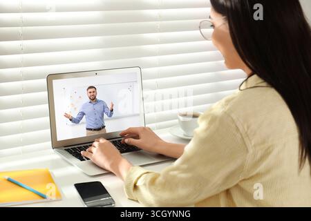 E-Learning-Konzept. Schüler, der Online-Videochat mit dem Lehrer über Laptop am Schreibtisch führt Stockfoto