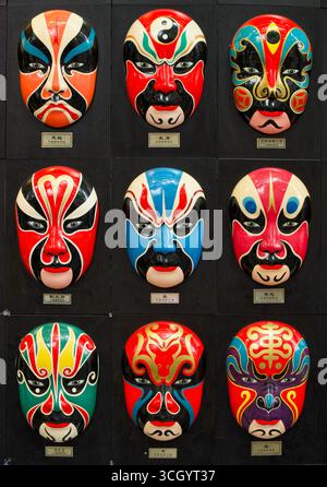 Bunte chinesische Theatermasken an einer Wand in einem Hutong in Peking, China Stockfoto