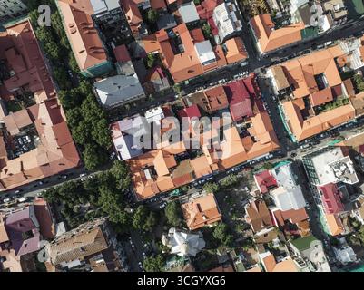 Aus der Vogelperspektive der sonnendurchfluteten Terrakotta-Dächer bilden einen auffälligen Kontrast zum tiefgrünen Laub und malen einen städtischen Wandteppich von oben, Batumi, Adjara, Georgia. Stockfoto