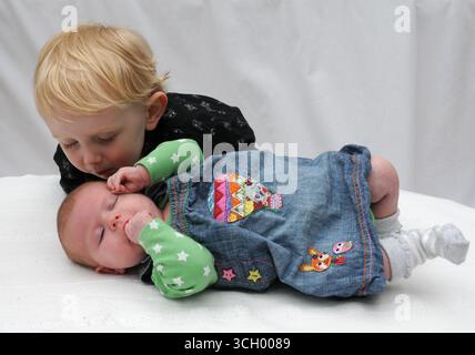 Der zweijährige Junge ist dabei, seine kleine Schwester zu küssen Stockfoto