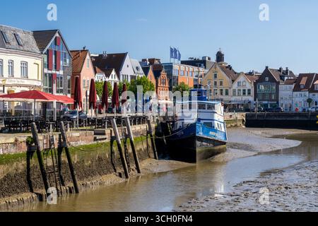 Husum, Deutschland - 30. Juni 2025: Blick auf das idyllische Stadtzentrum von Husum in Norddeutschland mit Booten, die bei Ebbe im Hafen liegen Stockfoto