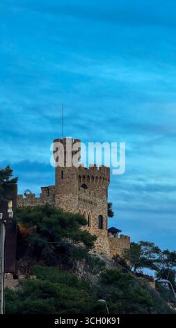 Malerischer Abendblick auf das berühmte Schloss in Lloret de Mar, Spanien, beleuchtet vor dem Abendhimmel, Wahrzeichen und Touristenattraktion Stockfoto