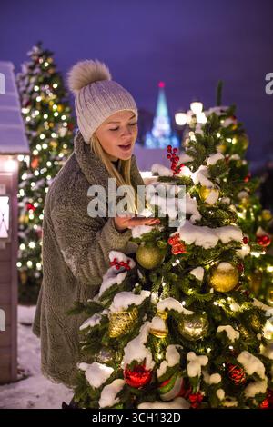 moskau, russland, 12.01.2020 Kaukasierin, die nachts im Freien Weihnachtsbaum genießt. Winterferienkonzept für festliche Feierlichkeiten. Happy New Stockfoto