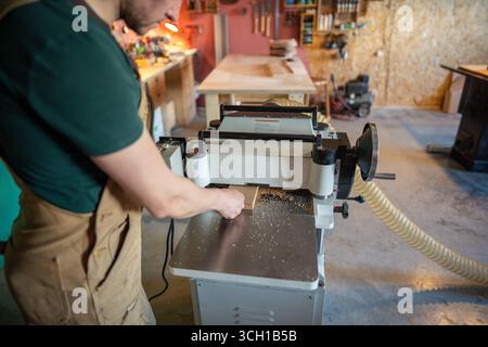 Erfahrener Handwerker, der mit Holz an Hobeldickengelenken arbeitet, Möbelmaterialien vorbereitet Stockfoto