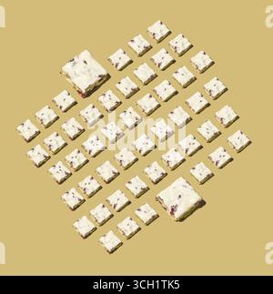 Eine künstlerische Überkopfaufnahme, die kleine Würfel aus weißem Nougat mit Nüssen zeigt, die in einem geometrischen Rautengitter über einer beigen Oberfläche angeordnet sind, um ein sauberes Bild zu schaffen Stockfoto