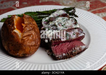 Ein weißer Teller mit Filet Mignon mit Diane-Sauce, gebackener Kartoffel und sautiertem Spargel Stockfoto