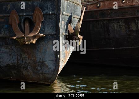 Ein rostiger Anker am Bug eines alten baufälligen Schiffes in einem Flusshafen. Stockfoto