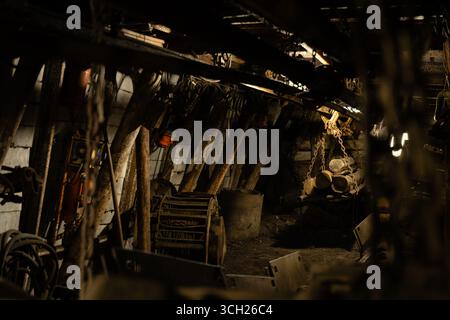 Schwach beleuchteter Bergbautunnel mit Lüftungsrohren, Kabeln und Förderband in einem verlassenen Kohlebergwerk in Tschechien. Stockfoto