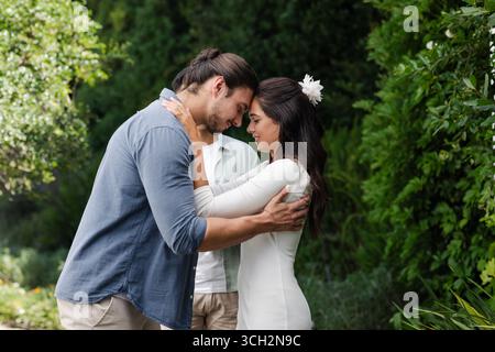 Ein Paar, das sich liebevoll im Garten umgibt und gemeinsam einen romantischen kleinen zwanglosen Hochzeitstag feiert Stockfoto