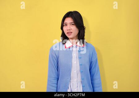 Junge Person posiert in blauem Pullover vor hellgelbem Hintergrund Stockfoto