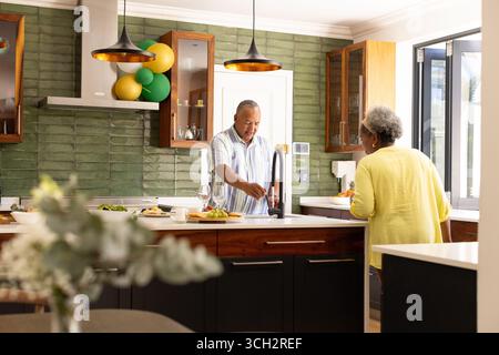 Seniorenpaar, das zusammen in der modernen Küche Essen zubereitet und Gespräche genießt Stockfoto