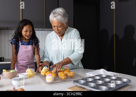 Cupcakes dekorieren, Großmutter und Kind in der modernen Küche, Zeit miteinander verbringen Stockfoto