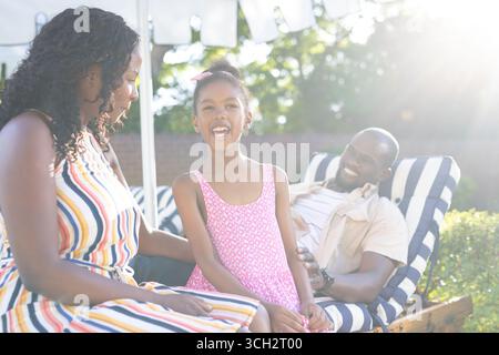 Afroamerikanische Familie genießt einen sonnigen Tag im Freien, lächelt und entspannt sich zusammen Stockfoto