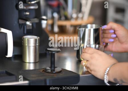 Cremona, Italien - 21. Juli 2025 Barista bereitet Espresso vor, gießen in ein kleines Glas mit Milchaufschäumender Pitcher, bereit für die Kaffeezubereitung Stockfoto
