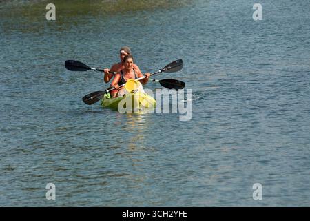Nigran,Pontevedra,Spanien;24. August 2025: Zwei Personen paddeln mit einem gelben Kanu auf dem ruhigen Wasser der A Foz-Mündung in Ramallosa, Nigran auf einer sonnigen Summe Stockfoto