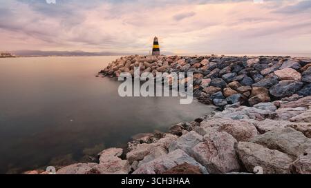 Malerische Küstenlandschaft von Benalmadena Malaga Spanien mit Leuchtturm, felsigem Ufer und dramatischen Sonnenuntergang Wolken über dem Mittelmeer Stockfoto