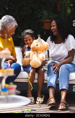 Auf einer Party, bei der im Garten Geburtstag gefeiert wird, Großmutter, Mutter und Kind mit Teddybär Stockfoto