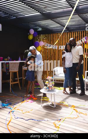 Auf der Party, feiert Geburtstag im Garten, Großvater umarmt Enkelin, Familie lächelt zusammen Stockfoto