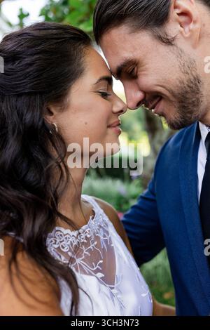 Braut und Bräutigam teilen intime Momente im Freien, lächeln und umarmen sanft Stockfoto