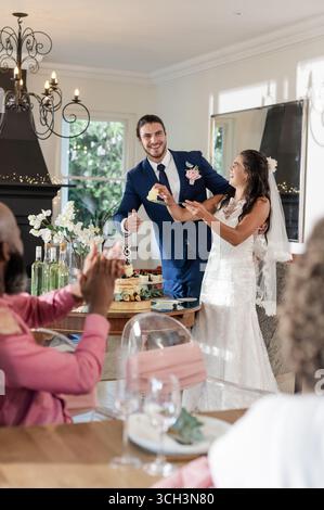 Braut und Bräutigam teilen sich bei der Hochzeitsfeier mit Applaus die Gäste Stockfoto