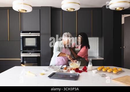 Backen in der Küche, Seniorenmutter und Erwachsene Tochter teilen einen freudigen Moment, zu Hause Stockfoto