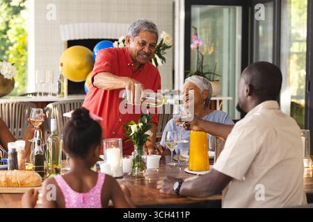 Wein gießen, Großvater bei verschiedenen Familientreffen, jeder hat Spaß im Garten Stockfoto