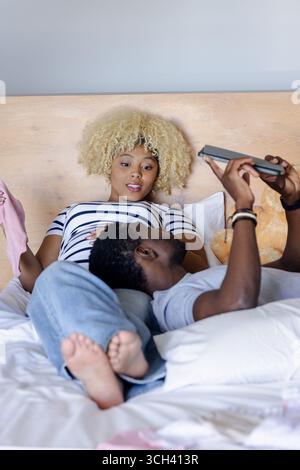 Entspannen Sie sich zu Hause, und Ihre Freunde genießen Gespräche, während Sie auf das Tablet im Bett schauen Stockfoto