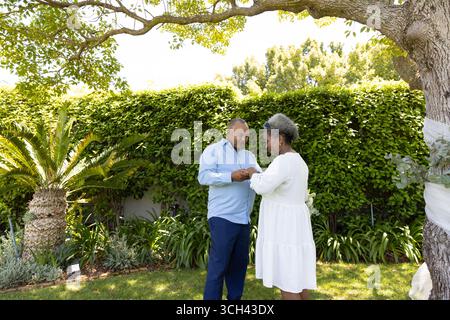 Seniorenpaar tanzt zusammen im Garten und genießt einen sonnigen Tag im Freien Stockfoto