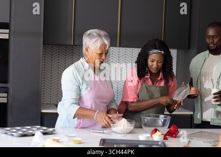 Gemeinsam in moderner Küche backen, afroamerikanische Familie lächelnd, drei Generationen Stockfoto