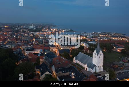 Die Skyline von Thisted, Dänemark bei Nacht, zeigt den glühenden Hafen, die weiße Kirche, die Lichter der Stadt und die malerische Küste am Limfjord Stockfoto