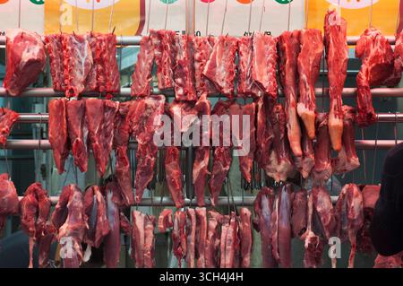 Eine Metzgerei in der Stadt Hongkong China, die verschiedene rohe Fleischsorten verkauft, die an Haken hängen. Stockfoto